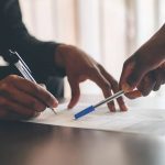 Deux personnes annotent un document de travail avec un stylo lors d'une réunion