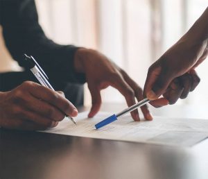 Deux personnes annotent un document de travail avec un stylo lors d'une réunion