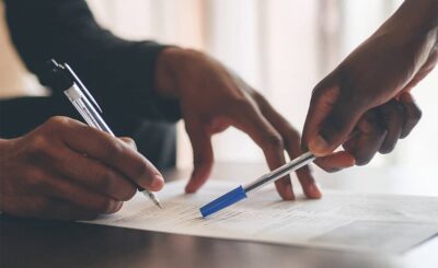 Deux personnes annotent un document de travail avec un stylo lors d'une réunion