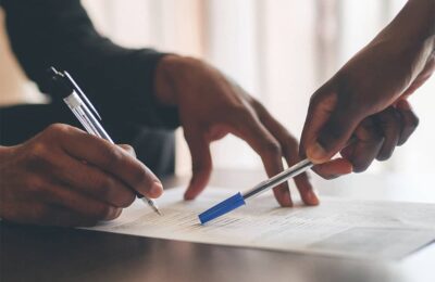 Deux personnes annotent un document de travail avec un stylo lors d'une réunion